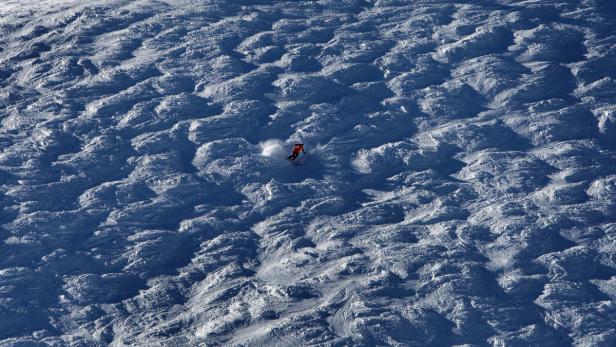 Ein Skifahrer fährt eine verschneite Piste hinunter.