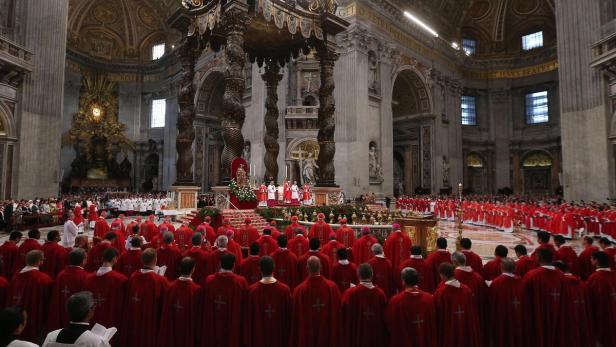 Eine große Menschenmenge in roten Gewändern versammelt sich im Petersdom in Rom.