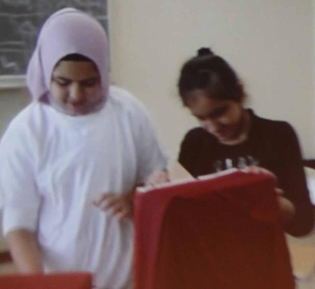 Zwei junge Frauen sitzen an einem Tisch und arbeiten.