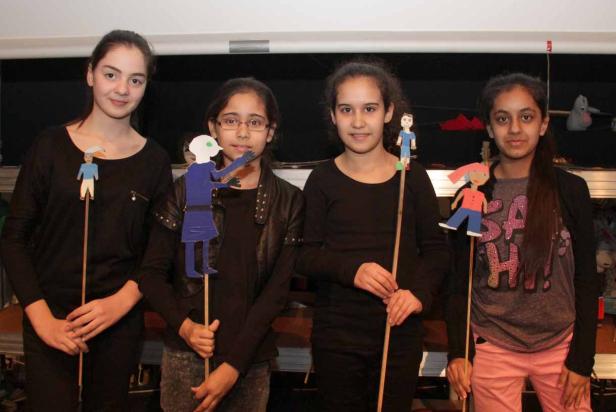 Vier Mädchen präsentieren selbstgebastelte Stabpuppen.
