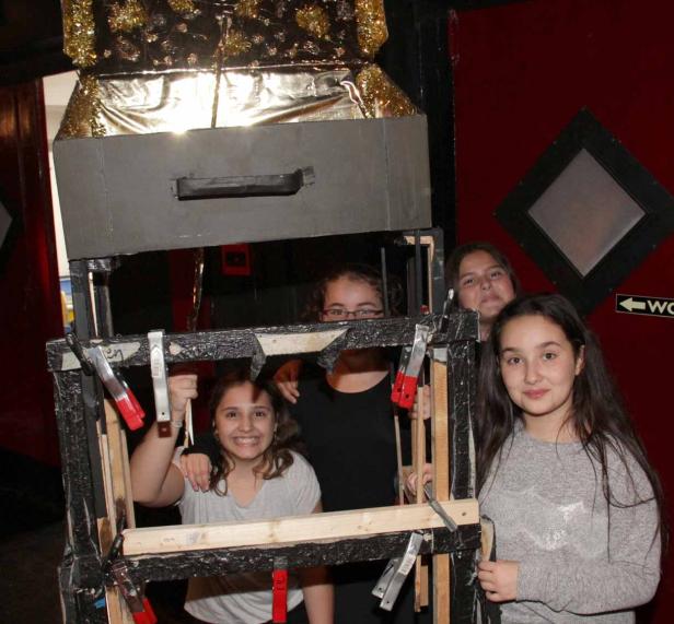 Vier junge Frauen posieren hinter einer selbstgebauten Fotokabine.