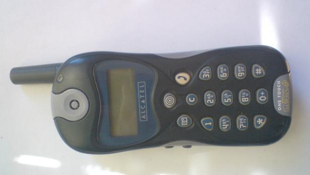 Ein älteres Alcatel One Touch Handy mit Antenne liegt auf einem Tisch.
