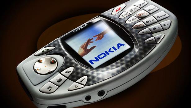 Ein silbernes Nokia-Handy mit einem Bild von zwei sich berührenden Händen auf dem Bildschirm.