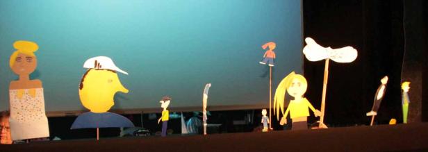 Eine Aufführung mit bunten Papierschattenfiguren auf einer Bühne.