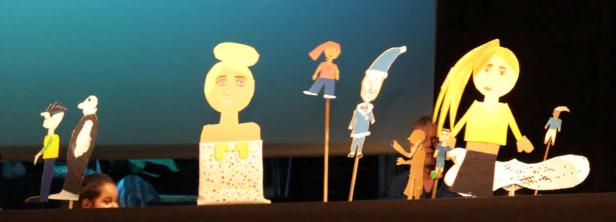 Eine Aufführung mit handgefertigten Marionetten vor einem blauen Hintergrund.