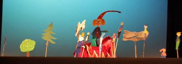 Eine Aufführung mit Marionetten vor einem blauen Hintergrund.