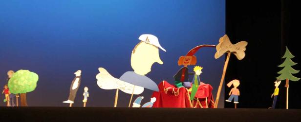 Eine Szene aus einem Marionettentheater mit verschiedenen Figuren und Kulissen.