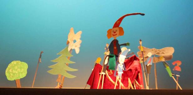 Eine Aufführung mit handgefertigten Marionetten vor einem blauen Hintergrund.