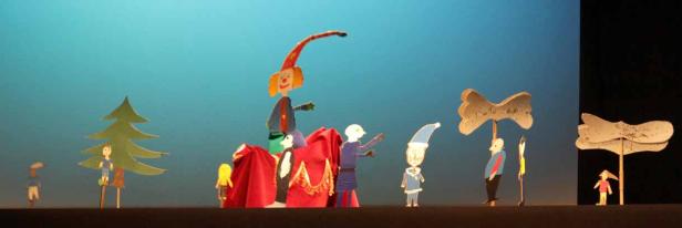 Eine Szene aus einem Marionettentheater mit verschiedenen Figuren und Kulissen.