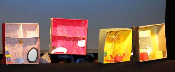 Mehrere Schuhkartons, die als Miniatur-Puppenhäuser mit glitzernden Dekorationen gestaltet sind.