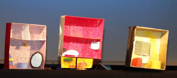 Drei bunte, selbstgemachte Zimmer aus Kartons stehen nebeneinander.