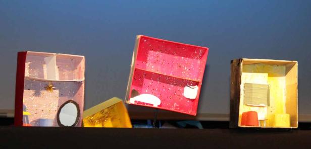 Drei bemalte Pappkartons stehen auf einer dunklen Oberfläche.