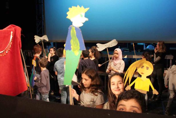 Kinder führen ein Puppentheaterstück auf einer Bühne auf.