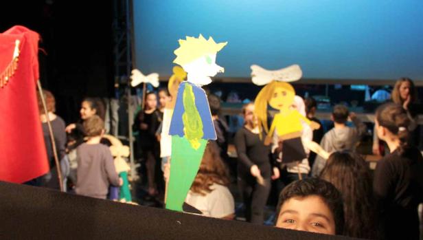 Eine Aufführung mit bemalten Pappfiguren vor einem Publikum.