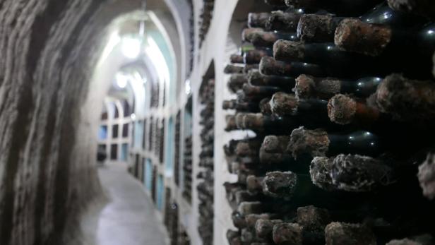 Ein langer Kellergang mit Regalen voller alter Weinflaschen.