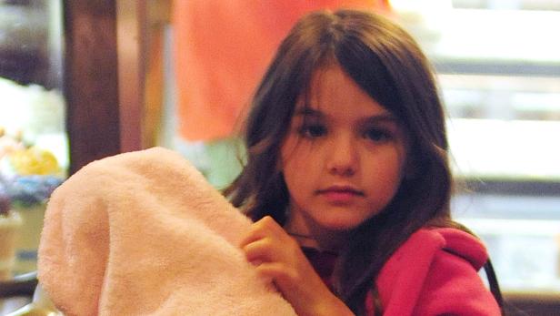 Ein junges Mädchen hält ein rosa Handtuch vor sich.