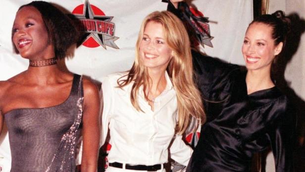 Naomi Campbell, Claudia Schiffer und Christy Turlington posieren lächelnd zusammen.