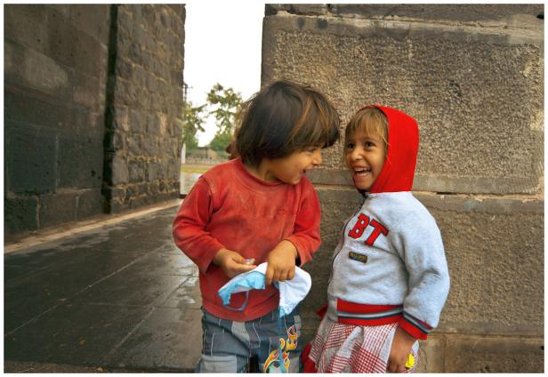 Zwei lachende Kinder stehen in einem Durchgang.