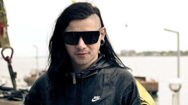 Skrillex posiert mit Sonnenbrille und Nike-Jacke vor einem Gewässer.