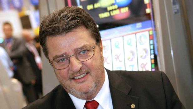 Ein Mann im Anzug steht vor einem Spielautomaten.