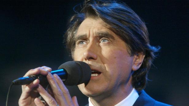 Bryan Ferry singt in ein Mikrofon.