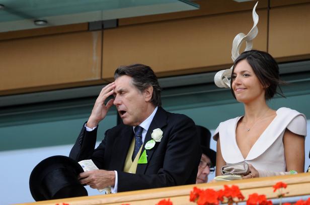 Ein Mann im Anzug und eine Frau mit Hut beobachten ein Ereignis.