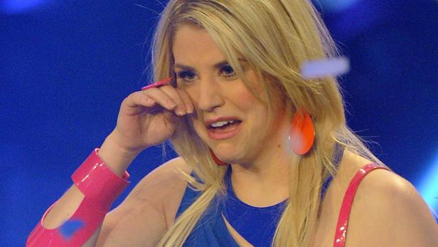 Eine blonde Frau mit Tränen in den Augen wischt sich eine Träne weg.