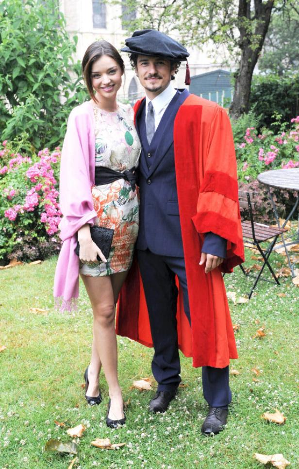 Miranda Kerr und Orlando Bloom posieren im Freien, Bloom trägt eine akademische Robe.
