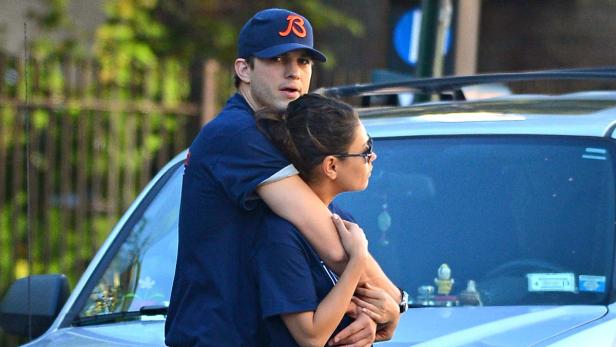 Ashton Kutcher umarmt Mila Kunis vor einem Auto.