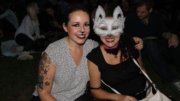 Zwei Frauen, verkleidet als Katzen, posieren für ein Foto.