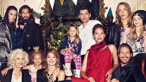 Eine Gruppe von Menschen unterschiedlichen Alters posiert für ein festliches Gruppenfoto.