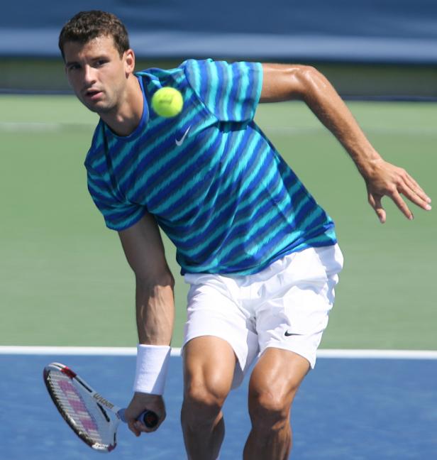 Ein Tennisspieler schlägt einen Ball auf einem Tennisplatz.