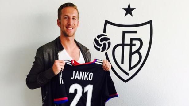 Ein Mann hält ein Trikot mit der Aufschrift „JANKO 21“ vor dem Logo des FC Basel.