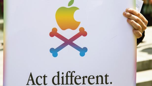 Ein Schild mit einem regenbogenfarbenen Apple-Logo über gekreuzten Knochen und dem Slogan „Act different.“.