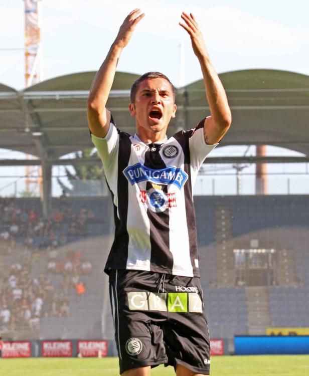 Ein Fußballspieler von Sturm Graz jubelt mit erhobenen Armen.