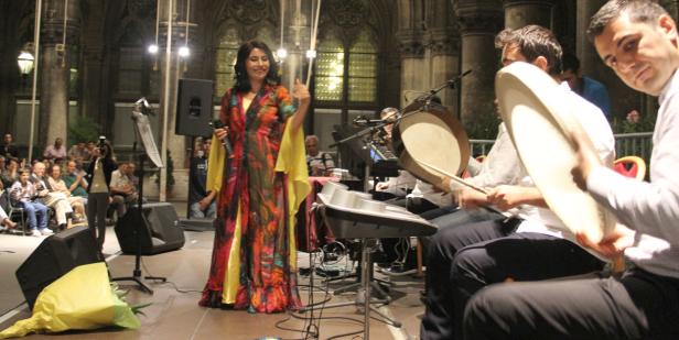 Eine Sängerin tritt mit ihrer Band vor Publikum auf einer Bühne auf.