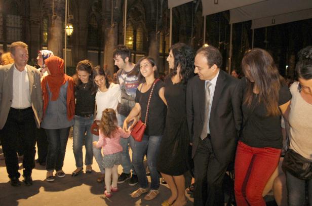 Eine Gruppe von Menschen, darunter ein kleines Mädchen, steht zusammen im Freien.