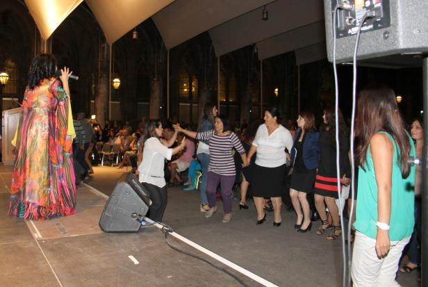 Eine Sängerin tritt auf einer Bühne auf, während eine Gruppe von Frauen tanzt.