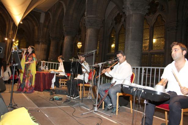 Eine Sängerin und ihre Band treten in einem Gebäude mit hohen Säulen auf.