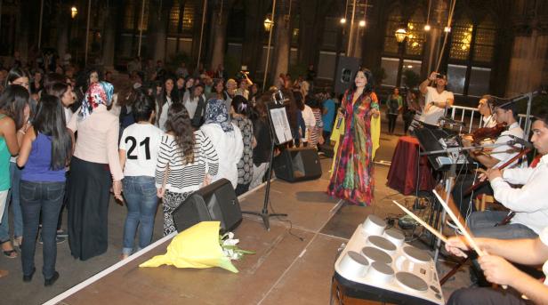 Eine Sängerin tritt mit ihrer Band vor einem Publikum im Freien auf.