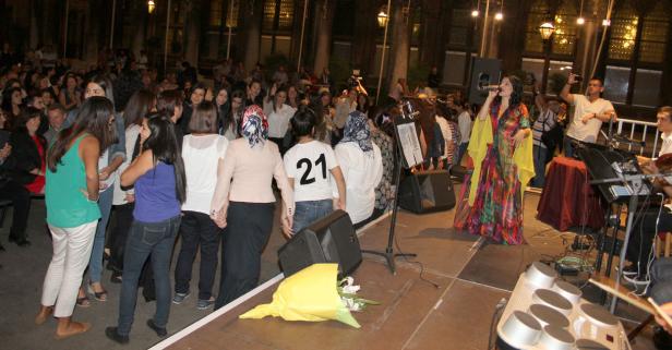 Eine Sängerin tritt auf einer Bühne vor einem Publikum auf, begleitet von einer Band.