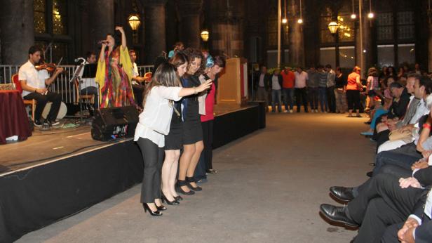 Eine Sängerin tritt mit ihrer Band vor einem Publikum auf, während einige Frauen tanzen.