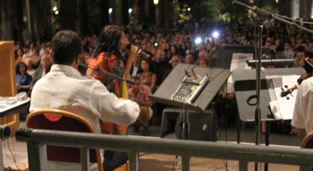 Eine Sängerin tritt mit einer Band vor einem großen Publikum auf.