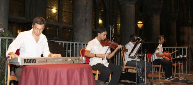Eine Band spielt auf einer Bühne mit Keyboard, Geige und Schlagzeug.