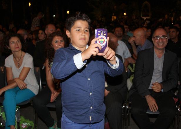 Ein Junge macht mit seinem lila Handy ein Foto von der Menschenmenge.