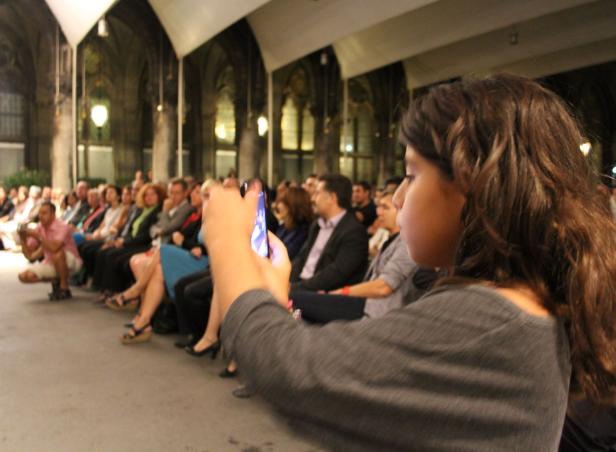 Eine Frau macht mit ihrem Smartphone ein Foto von einer Veranstaltung.