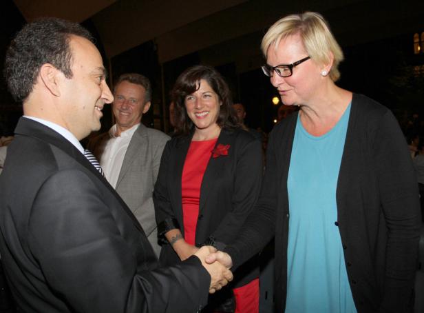 Ein Mann im Anzug schüttelt einer Frau mit Brille die Hand.