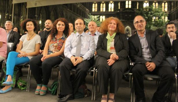 Eine Gruppe von Menschen sitzt bei einer Veranstaltung in einer Halle.