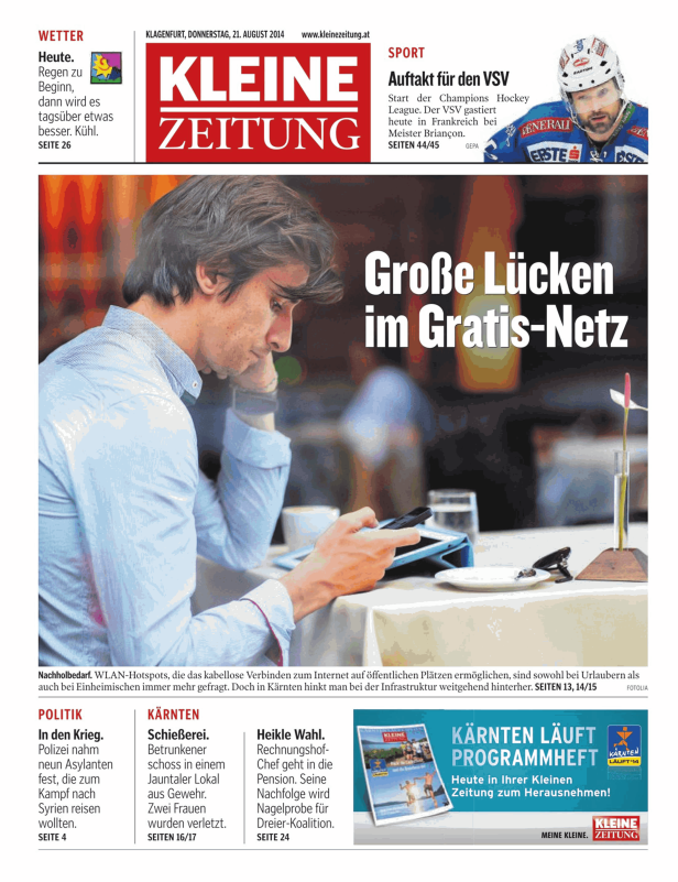 Ein Mann sitzt in einem Café und benutzt ein Tablet und ein Smartphone.