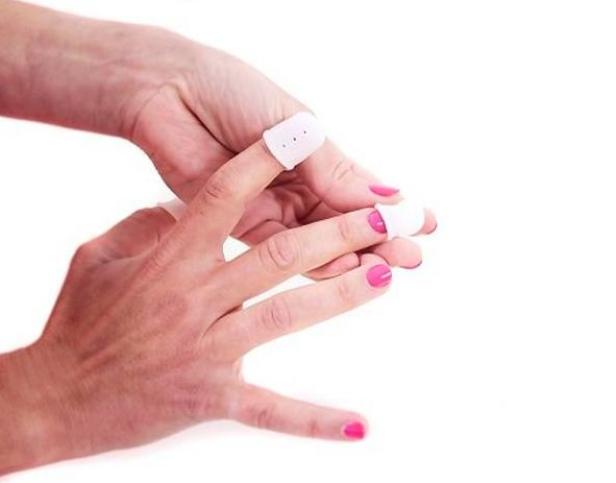 Eine Hand mit rosafarben lackierten Nägeln, an zwei Fingern befinden sich Fingerlinge.